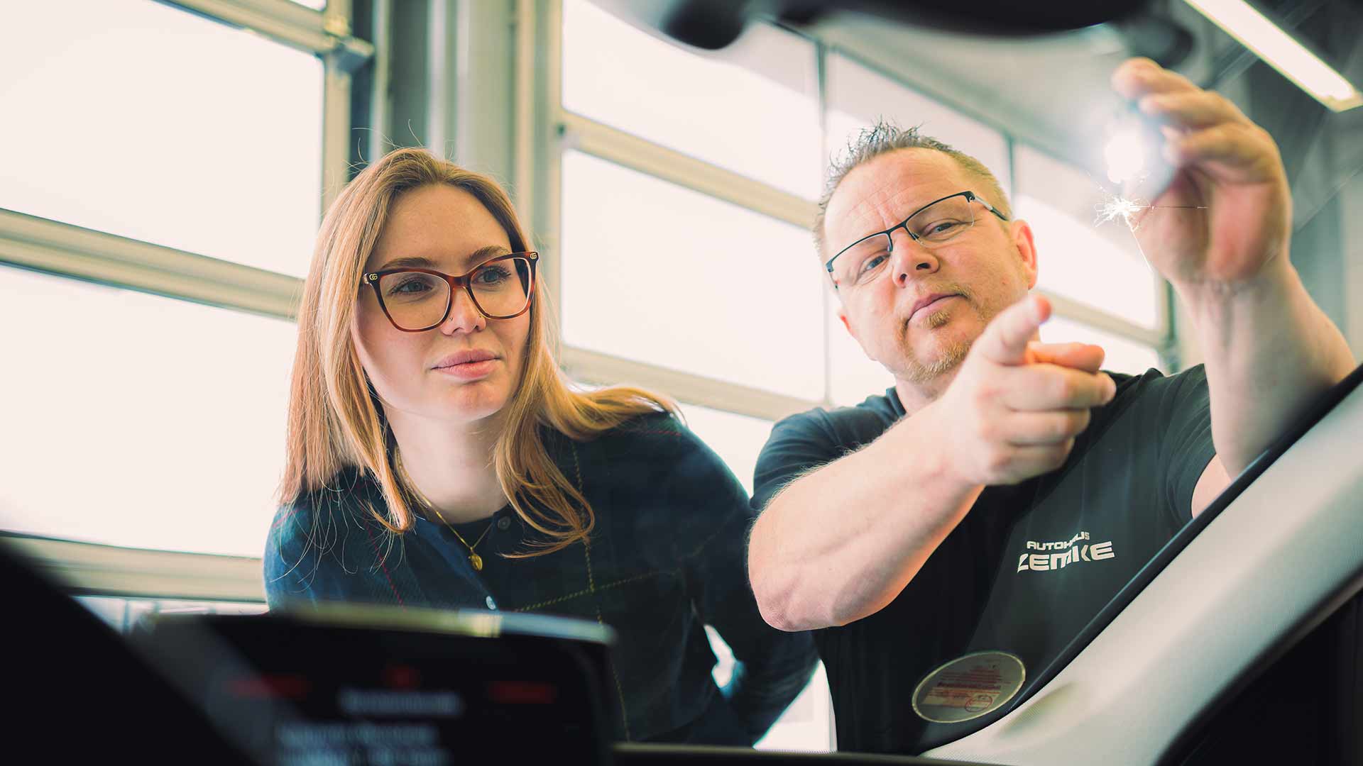Ein Mitarbeiter zeigt einer Dame einen Steinschlag in der Frontscheibe